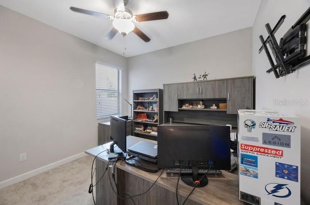 home office with a ceiling fan, baseboards, and light carpet