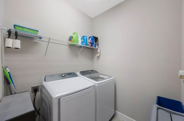 clothes washing area with washing machine and dryer and baseboards
