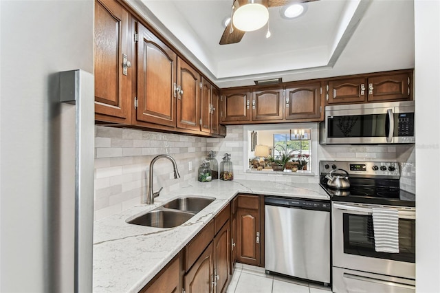 1 Boca Ciega Point Blvd Unit 310, Saint Petersburg, FL 33708 - kitchen featuring appliances with stainless steel finishes, a sink, decorative backsplash, light stone countertops, and light tile patterned flooring