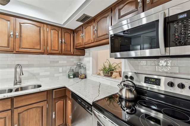 1 Boca Ciega Point Blvd Unit 310, Saint Petersburg, FL 33708 - kitchen with stainless steel appliances, a sink, brown cabinetry, and tasteful backsplash