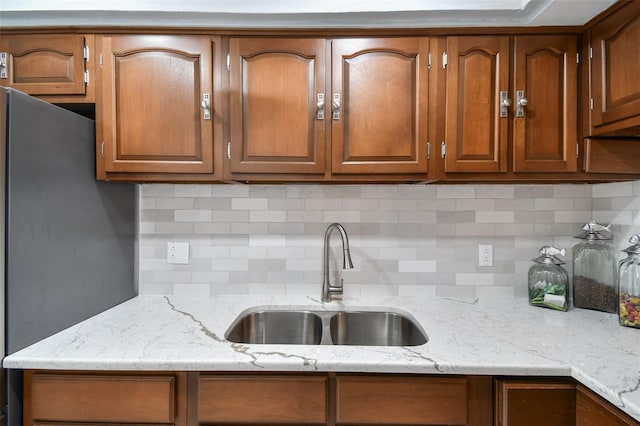 1 Boca Ciega Point Blvd Unit 310, Saint Petersburg, FL 33708 - kitchen featuring a sink, decorative backsplash, brown cabinetry, and light stone countertops