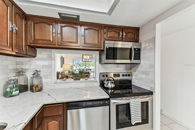 1 Boca Ciega Point Blvd Unit 310, Saint Petersburg, FL 33708 - kitchen featuring stainless steel appliances, light stone countertops, light tile patterned floors, and decorative backsplash