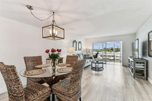 1 Boca Ciega Point Blvd Unit 310, Saint Petersburg, FL 33708 - dining area with light wood finished floors, a chandelier, and baseboards