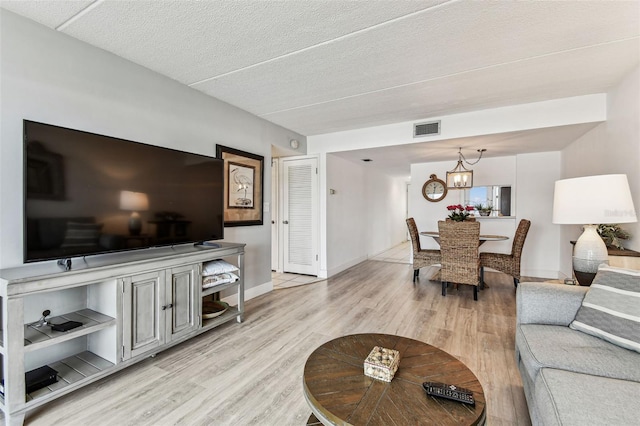 1 Boca Ciega Point Blvd Unit 310, Saint Petersburg, FL 33708 - living room featuring light wood finished floors, baseboards, a textured ceiling, and a chandelier