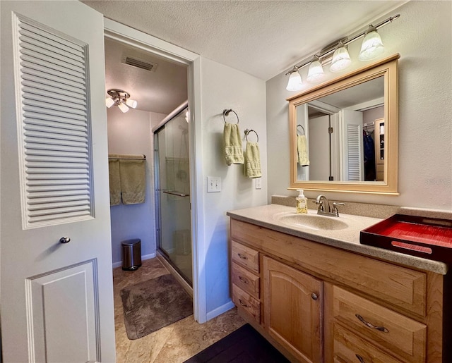 bathroom with a stall shower, vanity, and a textured ceiling