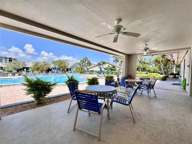 view of patio featuring a ceiling fan, a community pool, and outdoor dining space