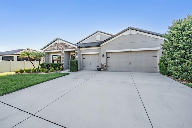 view of front of property featuring stone siding, an attached garage, driveway, and stucco siding