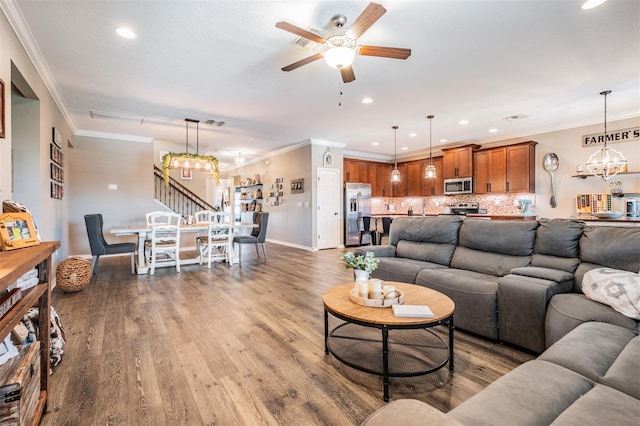 living room with a chandelier, a ceiling fan, wood finished floors, recessed lighting, and crown molding