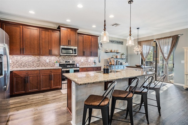 kitchen with stainless steel appliances, wood finished floors, a breakfast bar, backsplash, and crown molding