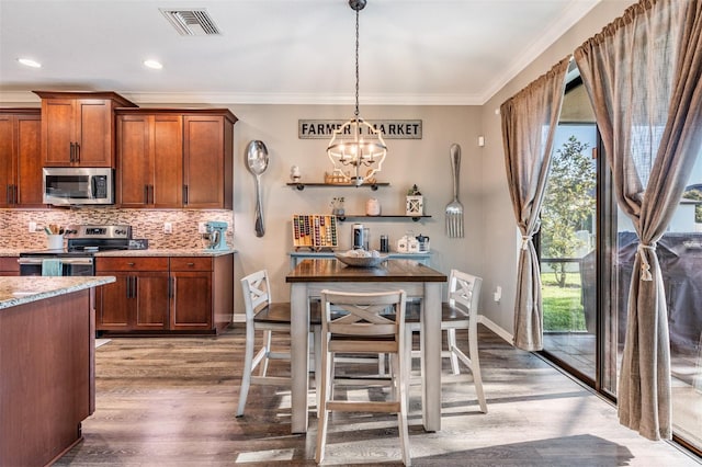 kitchen with stainless steel appliances, wood finished floors, crown molding, a chandelier, and tasteful backsplash