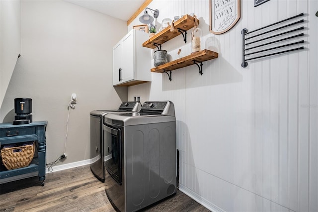 washroom featuring independent washer and dryer, cabinet space, wood finished floors, and baseboards