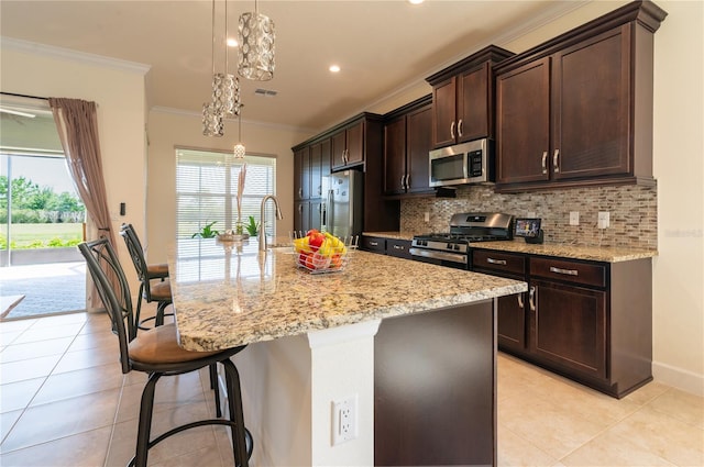 4888 Sevilla Shores Dr, Wimauma, FL 33598 - kitchen with stainless steel appliances, crown molding, light tile patterned floors, a kitchen breakfast bar, and decorative backsplash