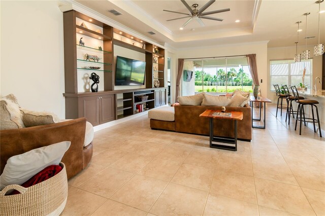 4888 Sevilla Shores Dr, Wimauma, FL 33598 - living room with ceiling fan, built in features, crown molding, a tray ceiling, and light tile patterned flooring