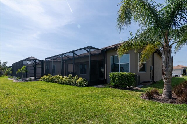 4888 Sevilla Shores Dr, Wimauma, FL 33598 - back of property with a yard, glass enclosure, and stucco siding