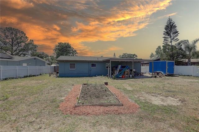 back of house at dusk featuring a vegetable garden