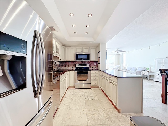100 Pierce St Unit 910, Clearwater, FL 33756 - kitchen featuring stainless steel appliances, dark countertops, cream cabinetry, open floor plan, and decorative backsplash