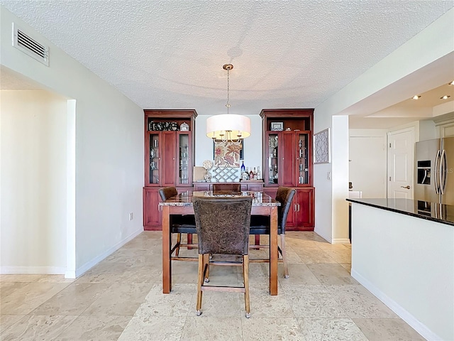 100 Pierce St Unit 910, Clearwater, FL 33756 - dining area with a textured ceiling, baseboards, and a chandelier