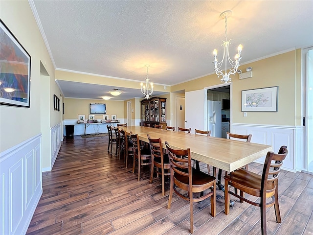 100 Pierce St Unit 910, Clearwater, FL 33756 - dining area featuring a chandelier, crown molding, dark wood-type flooring, a textured ceiling, and wainscoting