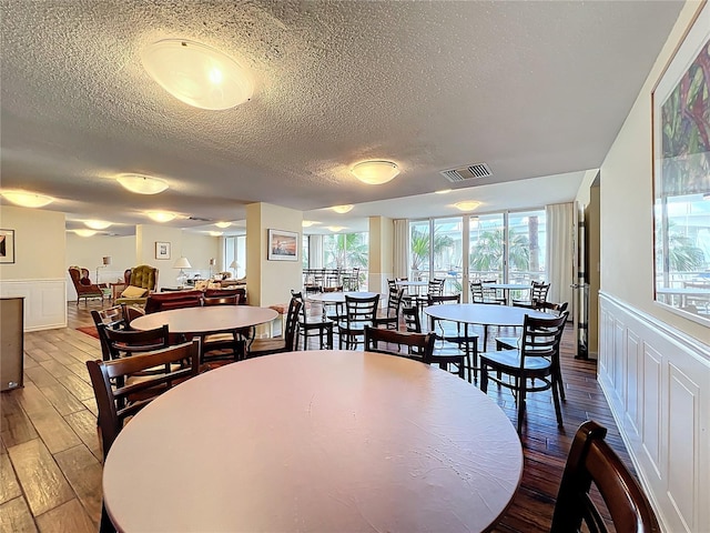 100 Pierce St Unit 910, Clearwater, FL 33756 - dining room with a textured ceiling, wood finished floors, a decorative wall, and a wainscoted wall