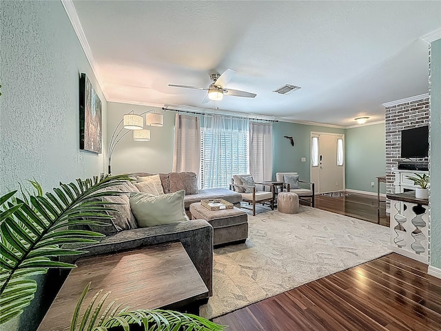 3093 Hillside Ln, Safety Harbor, FL 34695 - living room featuring ornamental molding, wood finished floors, ceiling fan, a textured wall, and a fireplace