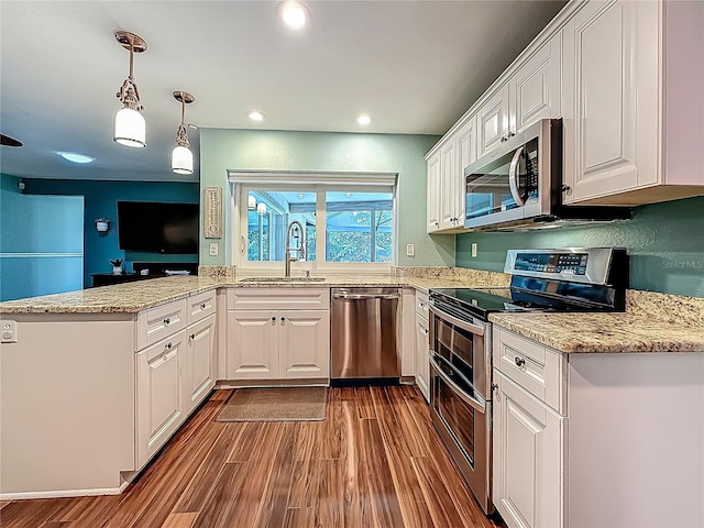 3093 Hillside Ln, Safety Harbor, FL 34695 - kitchen featuring stainless steel appliances, a sink, wood finished floors, white cabinetry, and a peninsula
