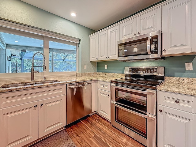 3093 Hillside Ln, Safety Harbor, FL 34695 - kitchen featuring appliances with stainless steel finishes, a sink, light wood-type flooring, white cabinetry, and a textured wall