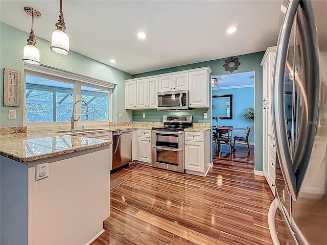 3093 Hillside Ln, Safety Harbor, FL 34695 - kitchen with stainless steel appliances, a sink, white cabinetry, a peninsula, and dark wood-type flooring