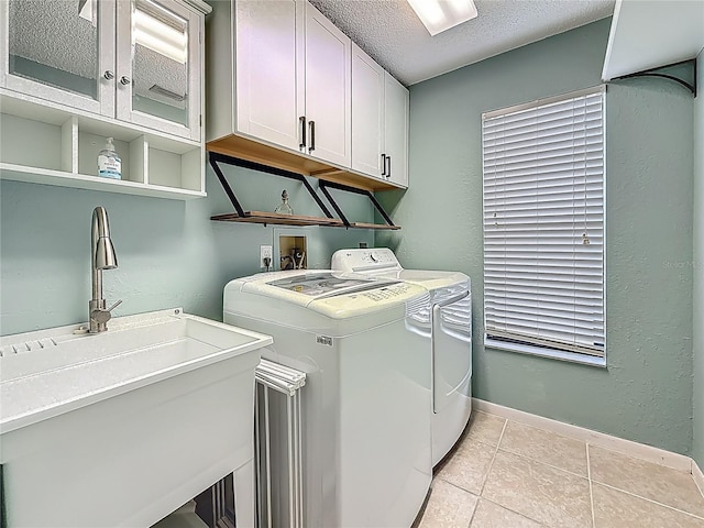 3093 Hillside Ln, Safety Harbor, FL 34695 - laundry area featuring washing machine and clothes dryer, cabinet space, a textured ceiling, light tile patterned flooring, and baseboards