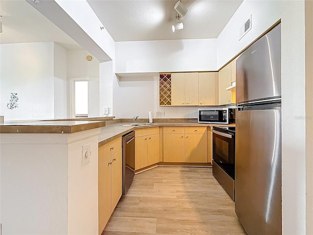 200 4th Ave S Unit 229, Saint Petersburg, FL 33701 - kitchen featuring appliances with stainless steel finishes, a peninsula, a sink, light wood finished floors, and light brown cabinetry