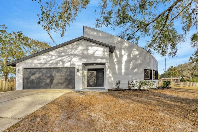 view of front of property with an attached garage, fence, and concrete driveway