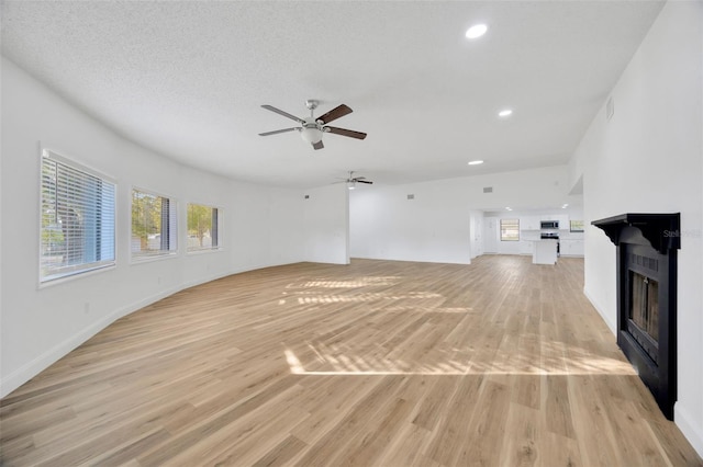 unfurnished living room with a fireplace, a ceiling fan, light wood-style floors, recessed lighting, and baseboards