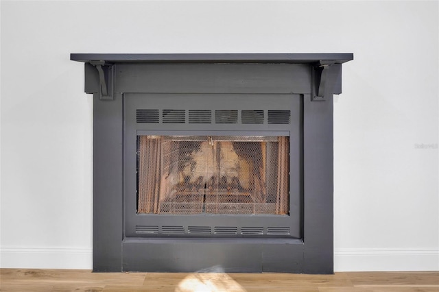 detailed view of baseboards, a fireplace, and wood finished floors