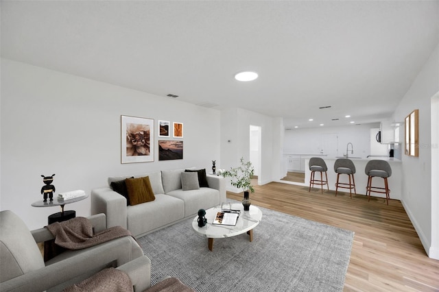living room with light wood finished floors, recessed lighting, and baseboards
