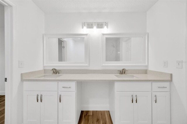 full bath with double vanity, wood finished floors, and baseboards