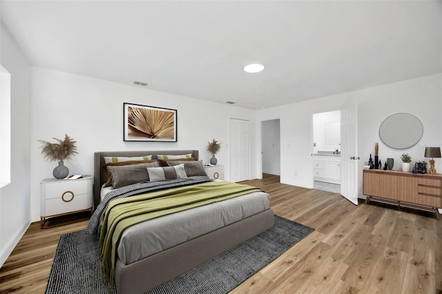 bedroom featuring wood finished floors, baseboards, and connected bathroom