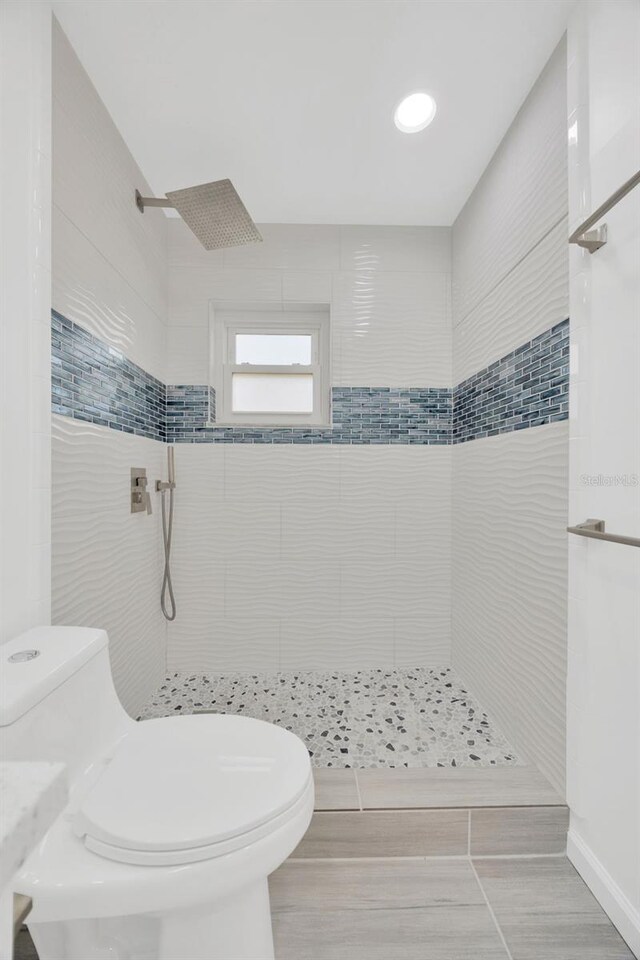 full bath with tiled shower and toilet