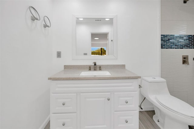 full bathroom featuring vanity, toilet, a tile shower, baseboards, and wood finished floors