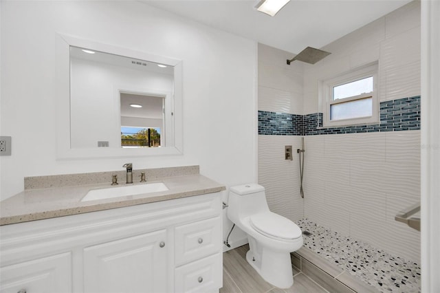 full bathroom with tiled shower, vanity, and toilet