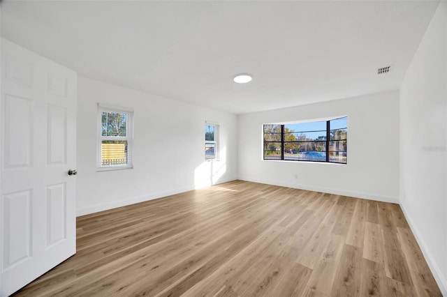 spare room with healthy amount of natural light, light wood finished floors, and baseboards