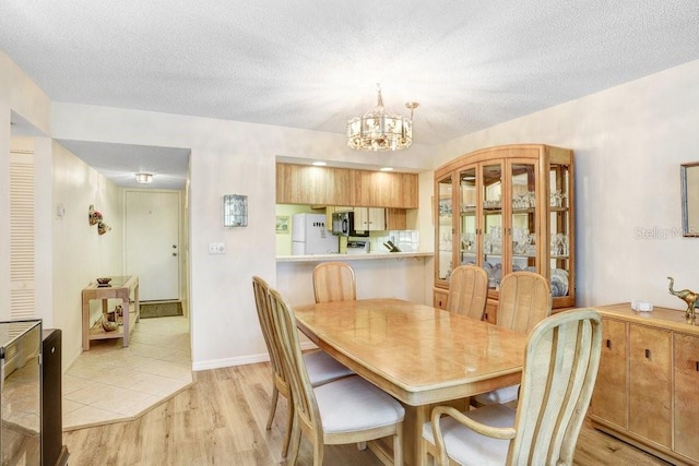 172 Lakeview Way Unit 172, Oldsmar, FL 34677 - dining space with light wood-style floors, a chandelier, and a textured ceiling