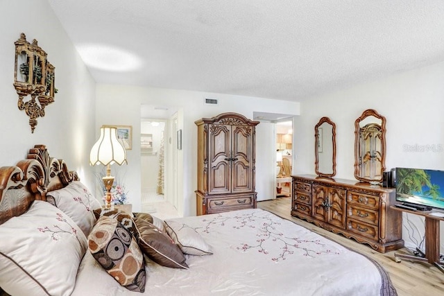 172 Lakeview Way Unit 172, Oldsmar, FL 34677 - bedroom with light wood finished floors, ensuite bath, and a textured ceiling