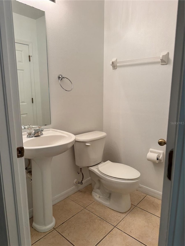 half bathroom with tile patterned floors, toilet, and baseboards