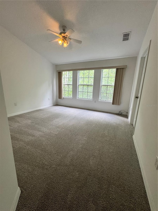 carpeted empty room with plenty of natural light, ceiling fan, baseboards, and a textured ceiling