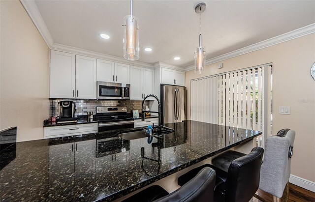 2706 11th Ct, Palm Harbor, FL 34684 - kitchen featuring stainless steel appliances, a sink, ornamental molding, decorative backsplash, and white cabinetry