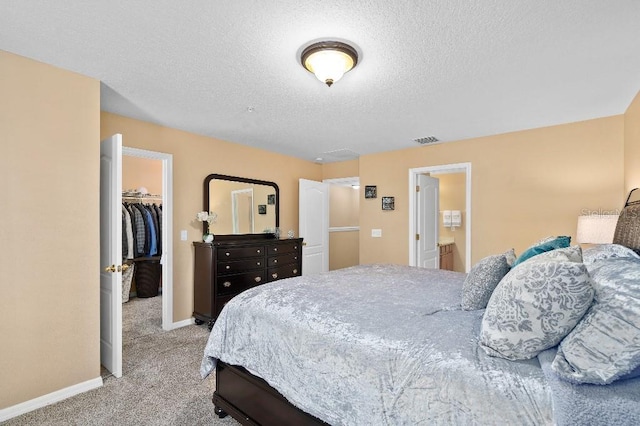 2417 Passamonte Dr Unit 1E, Winter Park, FL 32792 - bedroom featuring light colored carpet, a walk in closet, baseboards, a closet, and a textured ceiling