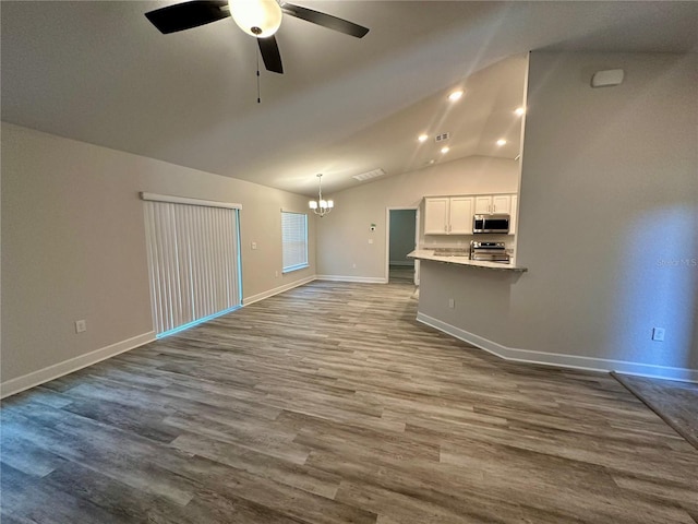 1259 Groveland Ln, Lakeland, FL 33811 - unfurnished living room featuring a chandelier, ceiling fan, dark wood-style flooring, baseboards, and vaulted ceiling