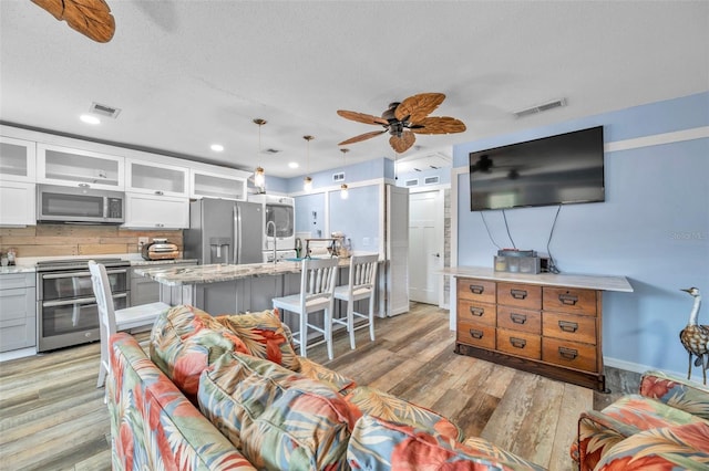 8931 Blind Pass Rd Unit 360, St Pete Beach, FL 33706 - living area featuring light wood-type flooring, baseboards, ceiling fan, a textured ceiling, and recessed lighting