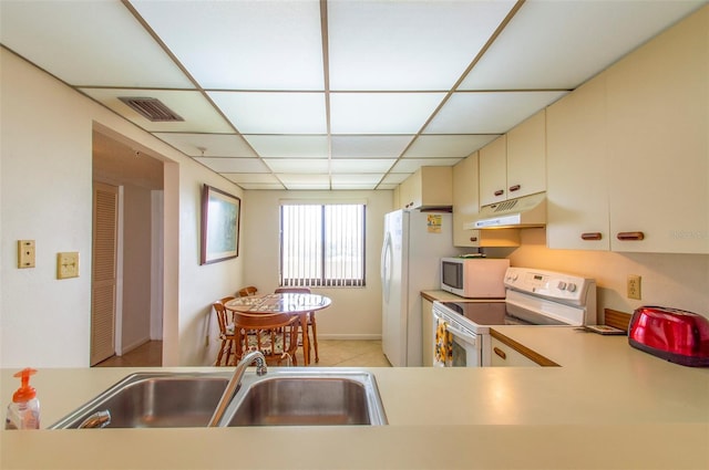 14950 Gulf Blvd Unit 603, Madeira Beach, FL 33708 - kitchen with white appliances, under cabinet range hood, a sink, cream cabinets, and a paneled ceiling