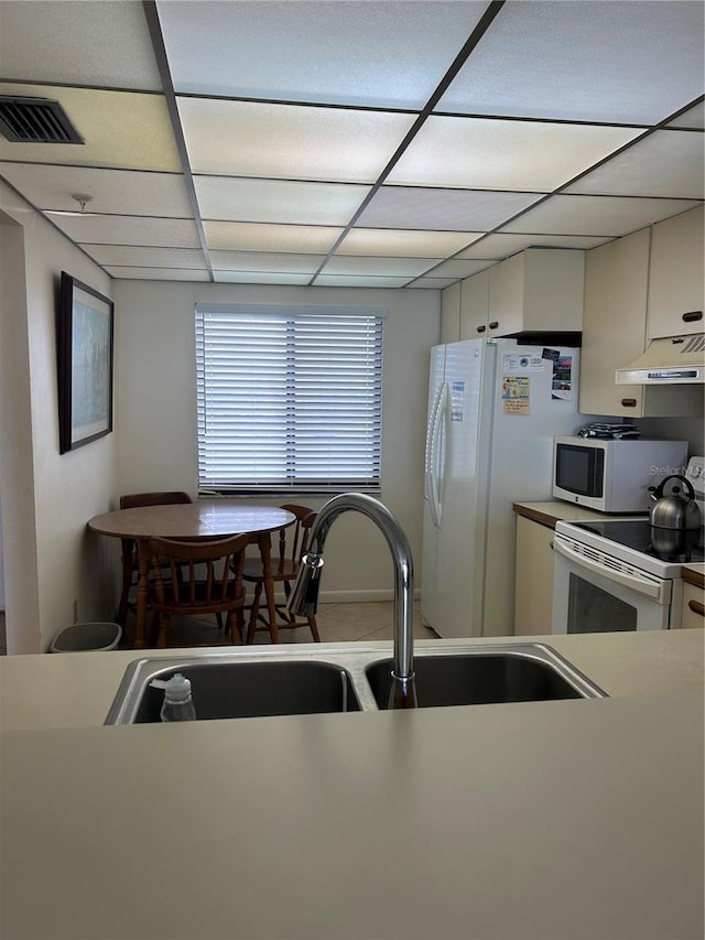 14950 Gulf Blvd Unit 603, Madeira Beach, FL 33708 - kitchen with under cabinet range hood, white appliances, a sink, a paneled ceiling, and white cabinetry