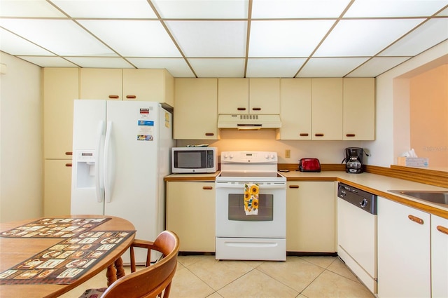 14950 Gulf Blvd Unit 603, Madeira Beach, FL 33708 - kitchen with white appliances, cream cabinetry, under cabinet range hood, a paneled ceiling, and light tile patterned flooring